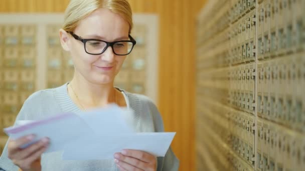 Portret van een jonge stijlvolle vrouw met een bundel brieven in haar handen in het postkantoor — Stockvideo