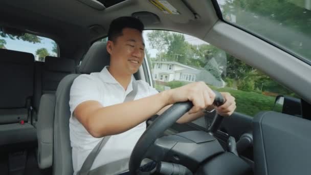 かわいいアジアの男は、小さなアメリカの町で運転を楽しんでいます。正面図 — ストック動画