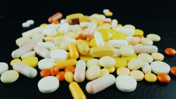 Pilules et capsules tombent dans un tas de médicaments sur un fond noir — Video