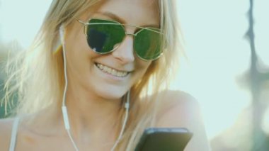 Bir akıllı telefon elinde tutan şık genç kadın kulaklıklar, müzik dinlemek.