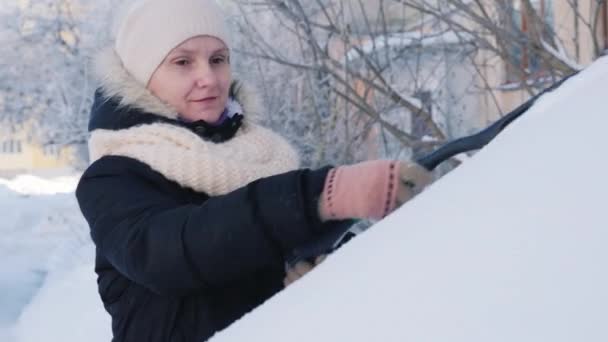 Mulher limpa o carro da neve com um pincel — Vídeo de Stock