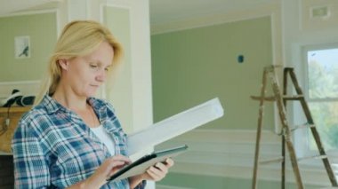 Genç bir kadın tasarımcı bir tablet nerede onarım devam etmekte olan yeni bir ev odaya kullanır..