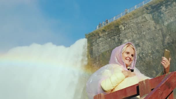 En glad turist fotograferar själv mot bakgrund av Niagara Falls — Stockvideo