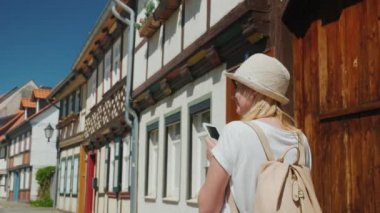 Bir kadın onun elinde bir akıllı telefon ile eski Alman şehir Wernigerode dar cadde boyunca yürüyor. Yaz tatili Almanya kavram