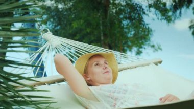 Genç bir kadın bir tatil zevk içinde bir tatil beldesi bir hamakta dinleniyor