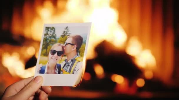 Un hombre quema una foto de una pareja enamorada y la arroja a la chimenea . — Vídeo de stock