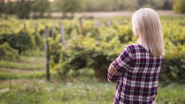 Junge Bäuerin blickt auf seinen Garten oder Weinberg — Stockfoto