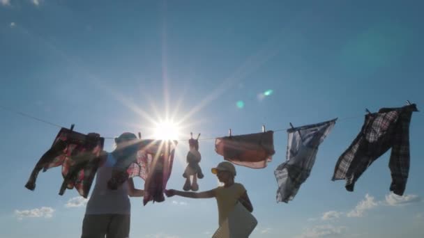 Fille aide maman accrocher des vêtements pour le séchage — Video