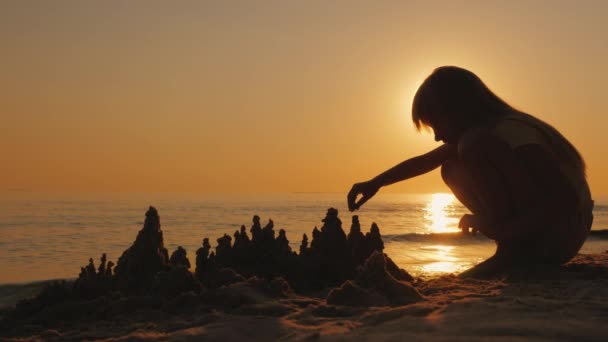 Un bambino gioca nella sabbia sulla spiaggia, costruisce un castello di sabbia — Video Stock