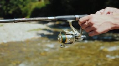 Fishermans elle dönen, küçük dağ nehir kenarında Balık tutma. Yan görünüm