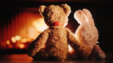 İki oyuncak bir kucaklama şömine yakın oturmak. Sıcaklık ve konfor ev kavram