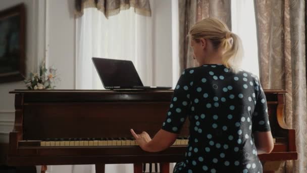 Kvinnan lära sig spela piano, tittar på laptop skärmen — Stockvideo