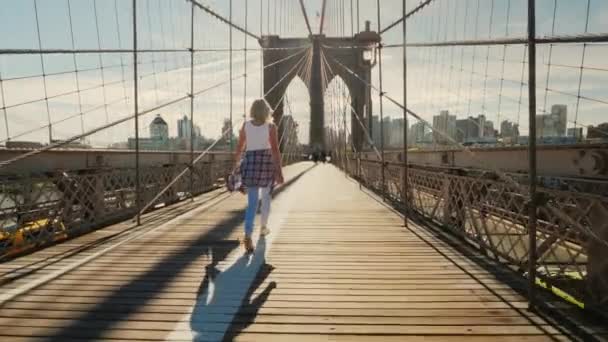 Une jeune femme active marche sur le pont de Brooklyn à New York — Video