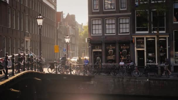 Amesterdam, Nederland, 2018 mei: de mooie straten van Amsterdam, de zon wordt weerspiegeld in het water van het kanaal. Aan de andere kant van het kanaal kan worden gezien Coffee Shop — Stockvideo