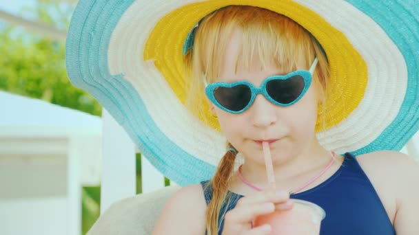 子供はプールで泳いだ後に休むフルーツカクテルを飲みます。子供との休日 — ストック動画