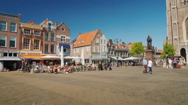 Delft, Pays-Bas, mai 2018 : La place centrale de Delft aux Pays-Bas. Cafés confortables et la population locale sur une promenade. À côté de la haute église — Video