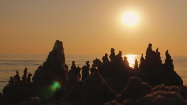 Silhouette of a sand castle against the background of the setting sun and sea waves — Stock Video