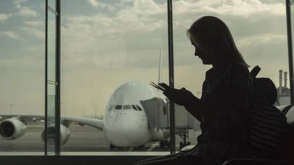 Mujer en la terminal del aeropuerto esperando el vuelo. Se sienta con pasaporte y tarjeta de embarque —  Fotos de Stock
