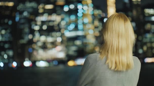 Ruční záběr blond ženy při pohledu na noční město, pohled zezadu — Stock video