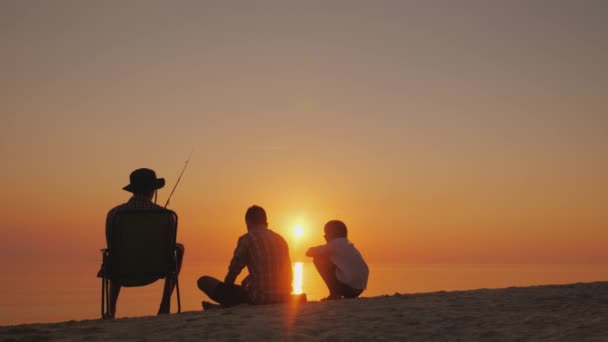 Trois enfants se reposent sur la rive du lac, ils pêchent. Loisirs dans l'air frais et concept de communication en direct — Video