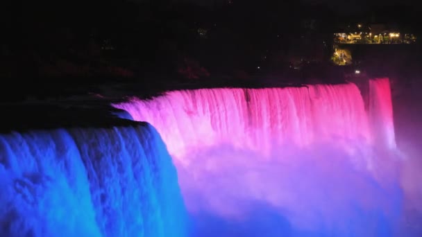 El lado americano de las Cataratas del Niágara, brillantemente iluminado por proyectores multicolores — Vídeos de Stock