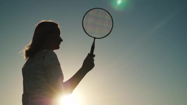 Mladá žena hrát badminton při západu slunce. Aktivní dovolená, koncept hry pod širým nebem — Stock video