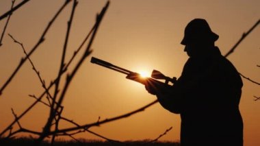 Bir adam ormanda avlar, bir optik görüş nişan alır