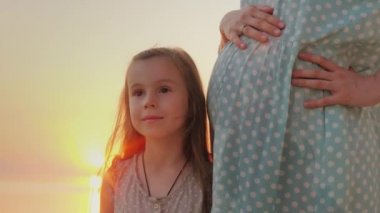 Küçük bir kız hamile annesi göbek duruyor