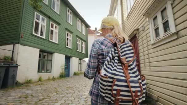 Elinde harita olan turist Norveç'te Bergen'in dar sokaklarında yürüyor. İskandinavya'da Tatil — Stok video