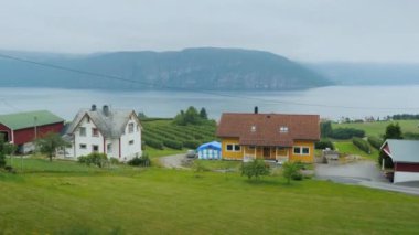 Fiyort kıyısında ride, bir arabanın penceresinden eski evler ve Norveç pitoresk doğasını görebilirsiniz
