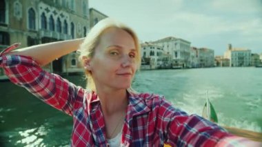 Kadın kendini Venedik 'teki bir kanaldaki binaların arka planında fotoğraflıyor. İtalya 'da turizm