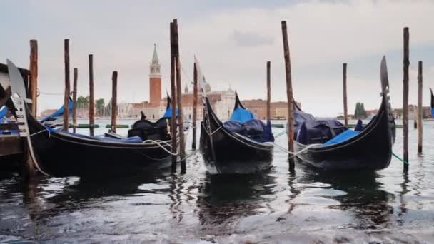 Три гондолы пришвартованы на фоне линии венецианского города — стоковое видео