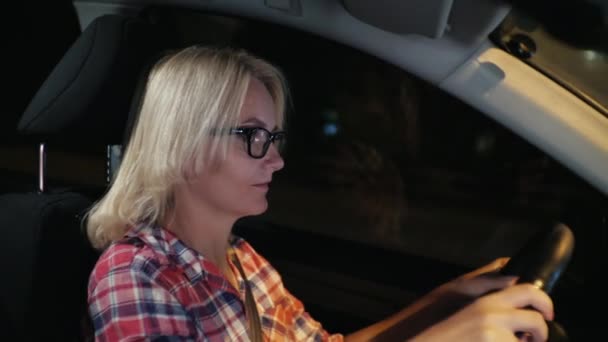 Guida femminile al volante di una macchina, guida attraverso la città di notte — Video Stock