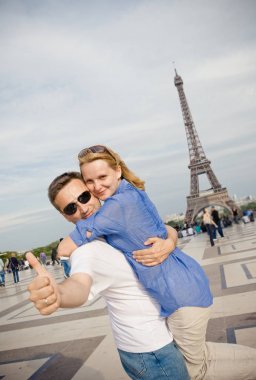 Paris'teki Eyfel Kulesi'nin arka planında mutlu genç bir çift. Avrupa'da Balayı