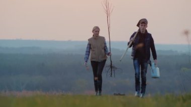 Bir fidan ve bir maça ile çiftçilerin bir çift devam bir ağaç dikmek için devam