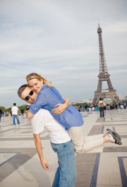 Paris'teki Eyfel Kulesi'nin arka planında mutlu genç bir çift. Avrupa'da Balayı