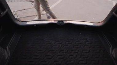 Woman puts shopping bags in the trunk of a car. Top view