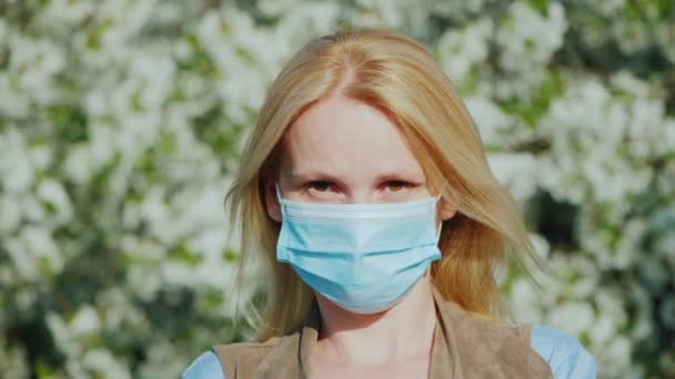A man in a gauze bandage against a background of flowering trees. Allergy during the spring flowering concept — Stock Video