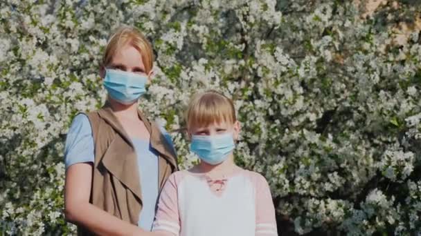 Woman with children in gauze bandages against the background of flowering trees. Allergy problems in the spring — Stock Video