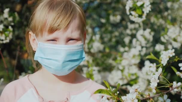 Portrait d'un enfant dans un bandage de gaze sur fond d'arbres à fleurs. Problèmes d'allergie — Video