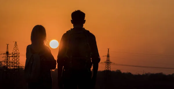 Twee tieners kijken uit naar de zonsondergang van een grote zon boven de stad — Stockfoto