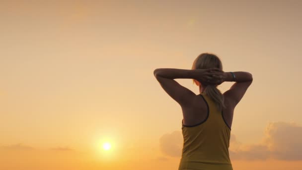 Actieve vrouw van middelbare leeftijd kijkt uit naar de zee, waar de zon opkomt. Begin een nieuwe dag en een gezonde levensstijl — Stockvideo