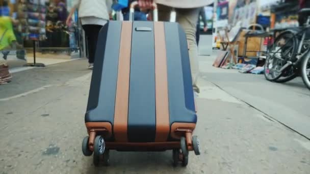 Une personne avec un sac sur roues descend le trottoir animé de Manhattan à New York — Video