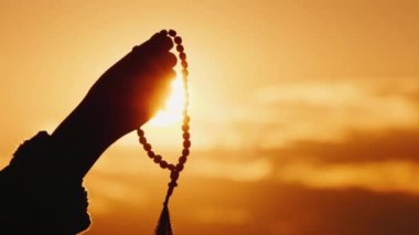 El gökyüzüne ve batan güneşe karşı tespih tutar, samimi dua ve meditasyon