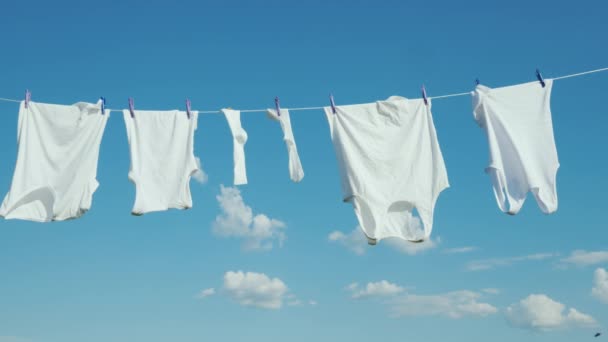 Linge blanc sèche sur une corde contre un ciel bleu propre — Video