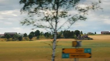 Norveç'in taşrasında seyahat edin, dramatik bir gökyüzünün arka planında tarım arazileri boyunca yolculuk edin