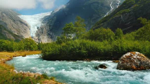 山の氷河を背景に、山の流れの中の水をきれいにします。ブリクスダル氷河とノルウェーの自然 — ストック動画