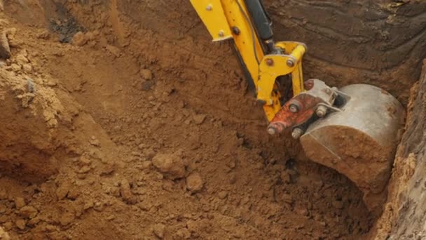 Secchio escavatore estrae terra dalla trincea. Lavori di scavo nel cantiere — Video Stock