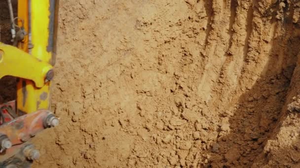 Ο κάδος εκσκαφέας που οδηγείται από ισχυρά υδραυλικά αφαιρεί το χώμα από την τάφρο. Τοποθέτηση αγωγών — Αρχείο Βίντεο