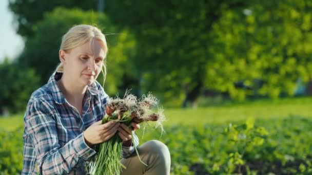 Mujer sosteniendo cebollas verdes frescas, recién arrancadas del jardín — Vídeo de stock